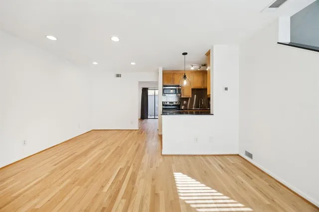 a view of an empty room with kitchen and a window