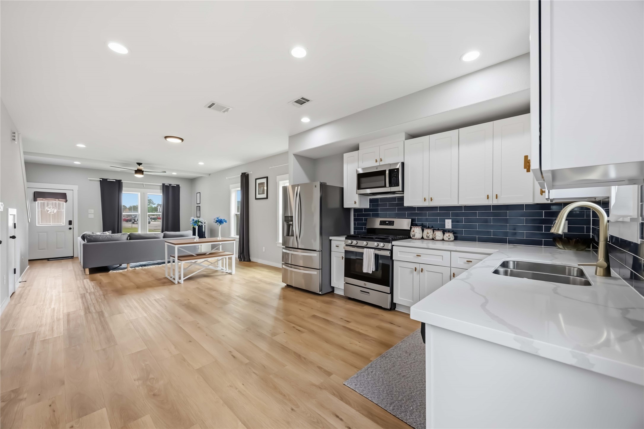5403 Amy Street Houston, TX 77028 - Photo 11 of 28 a large white kitchen with stainless steel appliances granite countertop a stove a sink a refrigerator and white cabinets with wooden floor