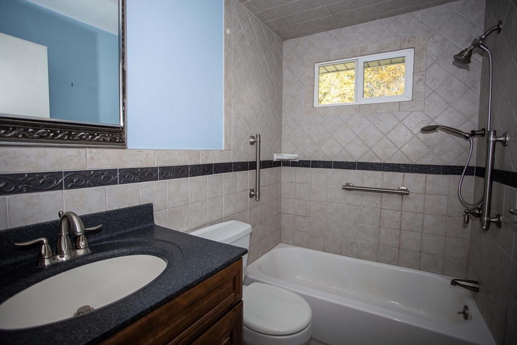 14 Sycamore Road Wakefield, MA 01880 - Photo 15 of 42 a bathroom with a granite countertop sink a toilet a mirror and bathtub