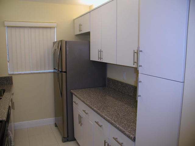 762 High Point Boulevard North, Unit D Delray Beach, FL 33445 - Photo 16 of 43 a kitchen with a refrigerator and cabinets
