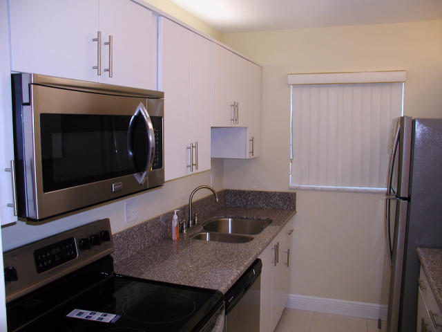 762 High Point Boulevard North, Unit D Delray Beach, FL 33445 - Photo 9 of 43 a kitchen with a sink stove and refrigerator