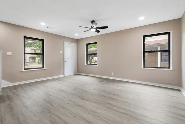a view of an empty room with a window and wooden floor