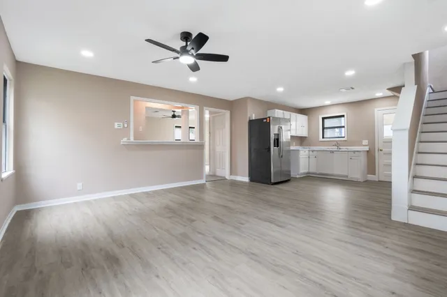 a view of a kitchen with a refrigerator a ceiling fan and wooden floor