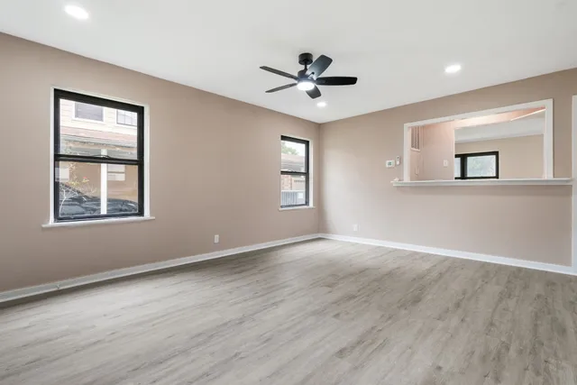 a view of an empty room with a window and wooden floor