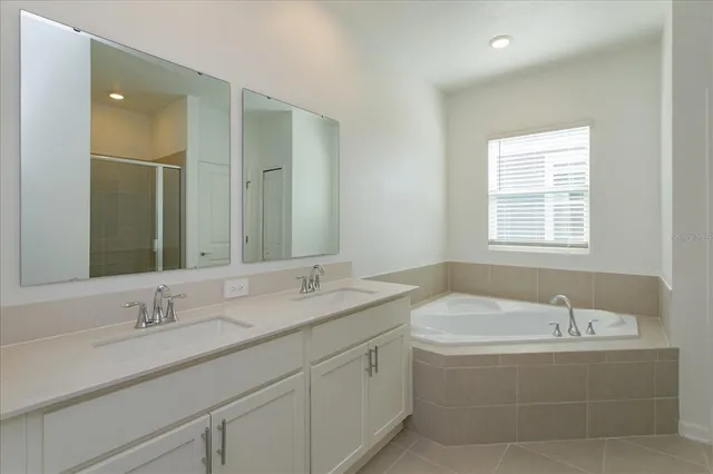 a bathroom with a granite countertop bathtub sink double and mirror