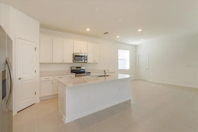 a kitchen with stainless steel appliances a refrigerator sink and white cabinets