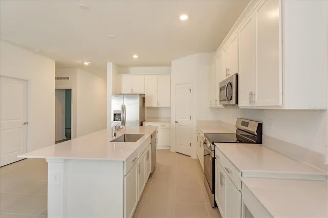 a kitchen that has a lot of white cabinets and stainless steel appliances