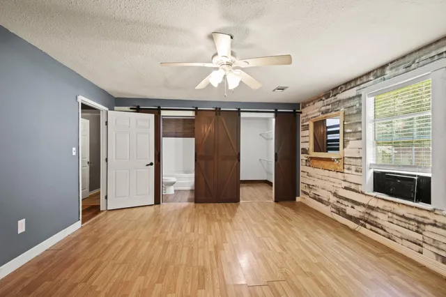 a view of an empty room with wooden floor fireplace and a window