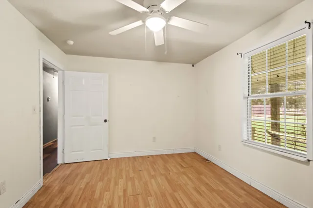 a view of an empty room with wooden floor and a window