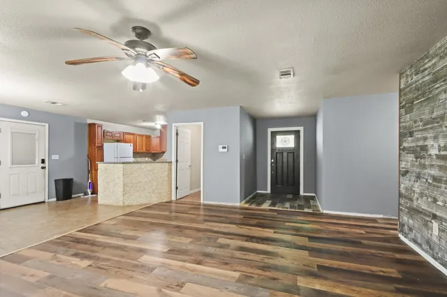 a view of a livingroom with a chandelier fan and a wooden floor