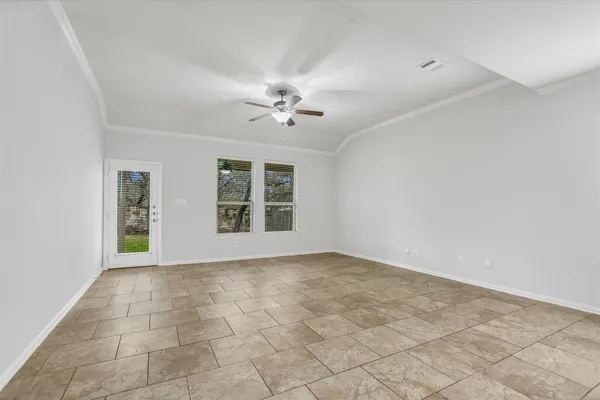 an empty room with windows and chandelier fan