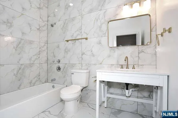 a bathroom with a sink toilet a mirror and bathtub