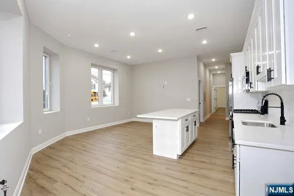 a large kitchen with stainless steel appliances a large center island wooden floor and a sink