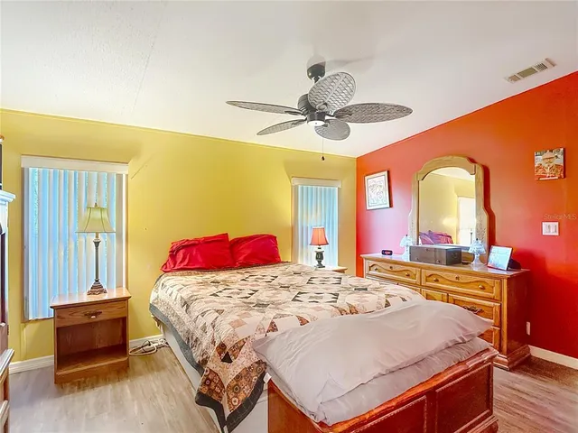 a bedroom with a bed dresser and wooden floor