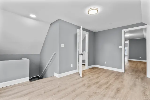 an empty room with wooden floor and entrance