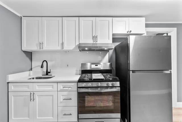 a kitchen with refrigerator a stove a sink and cabinets