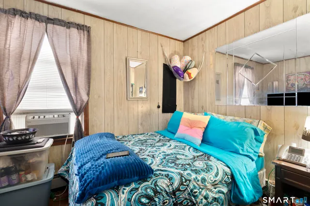 a bedroom with a bed a dresser and a large window