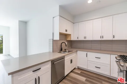a kitchen with white cabinets appliances and a sink