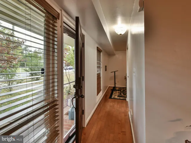 a view of a hallway with wooden floor and a bathroom