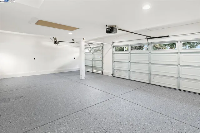 a view of an empty room and kitchen with furniture wooden floor and fan