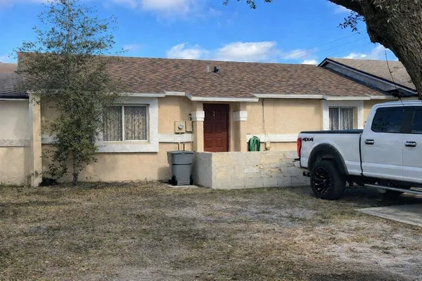 a view of a house with a barbeque grill and a large tree