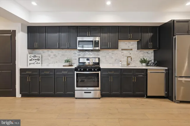 a kitchen with stainless steel appliances granite countertop a stove a refrigerator and a sink with wooden cabinets