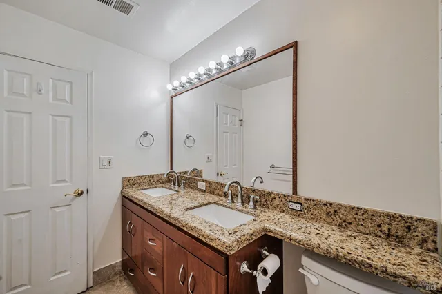 a bathroom with a granite countertop sink mirror vanity and toilet