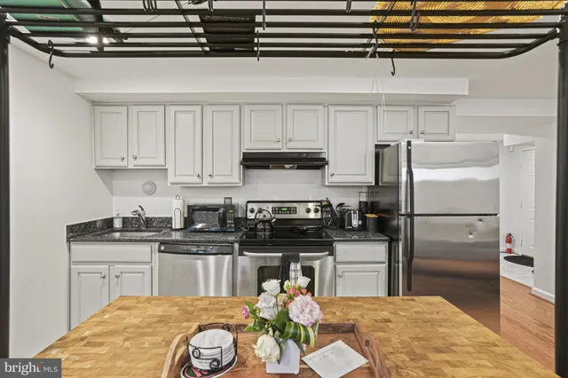 a kitchen with stainless steel appliances granite countertop a sink a stove and refrigerator