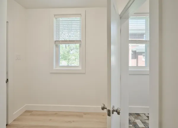 a view of an empty room with wooden floor and a window