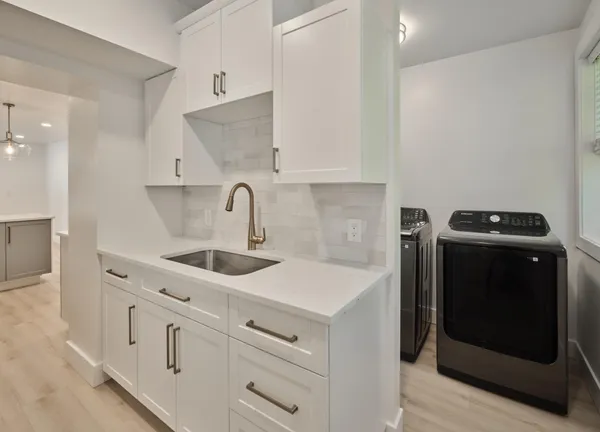 a kitchen with white cabinets and sink