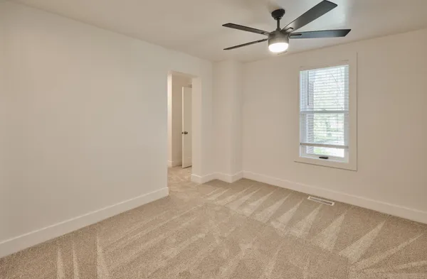 an empty room with windows and fan