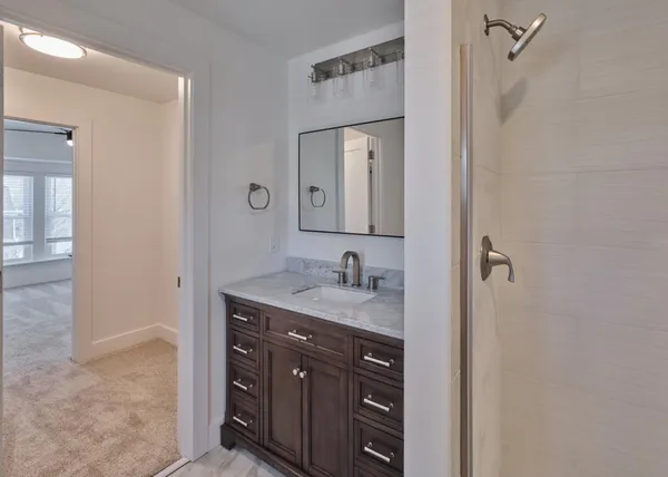 a bathroom with a granite countertop sink a mirror and a shower