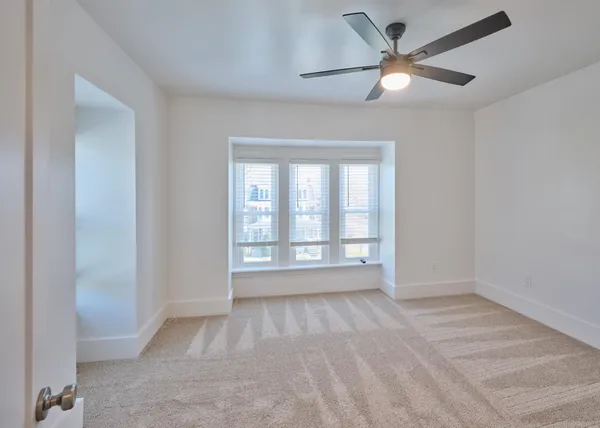 an empty room with fan and windows