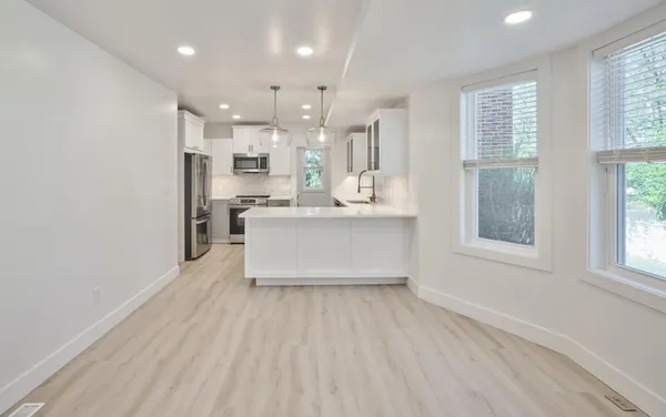 a large white kitchen with a white countertops a sink and a large window