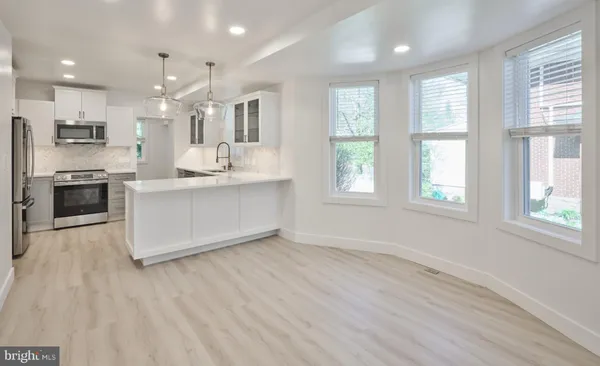 a large white kitchen with a large window a sink and stainless steel appliances