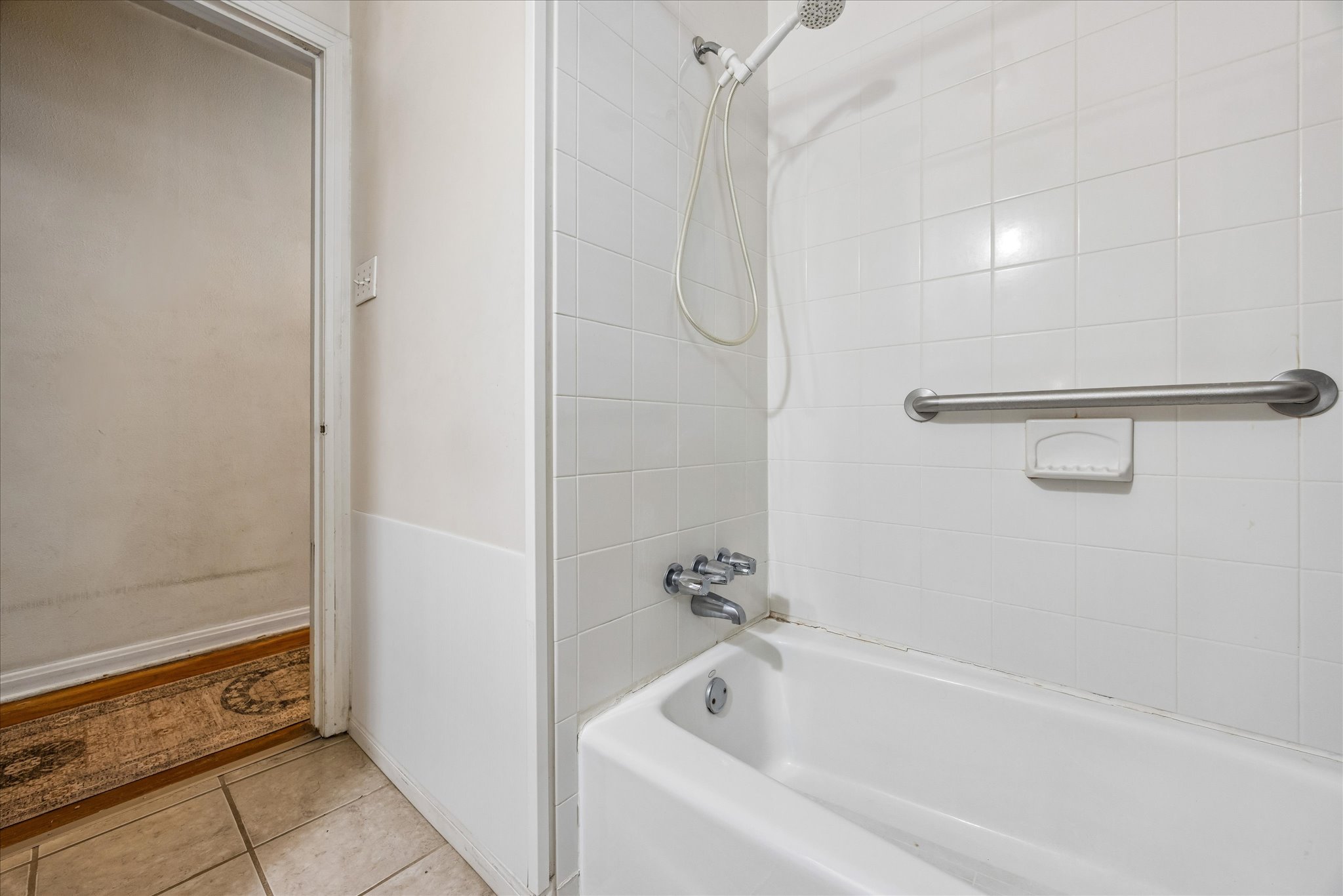 2009 Fort View Road Austin, TX 78704 - Photo 22 of 40 A well-maintained tub and shower with white tiled walls provide a clean, functional bathing space.