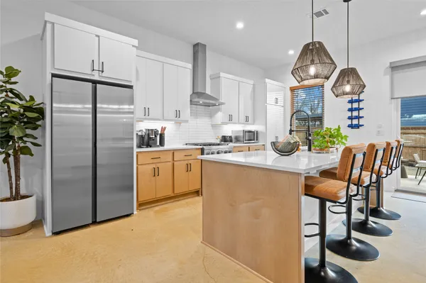 a kitchen with stainless steel appliances granite countertop a sink a stove a refrigerator cabinets and a dining table