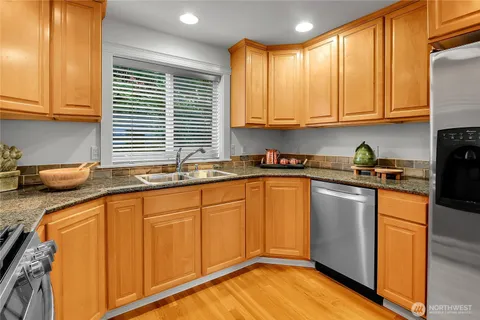 a kitchen with stainless steel appliances granite countertop a sink window and cabinets