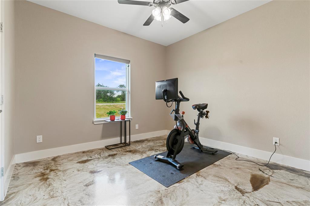 139 Kriston Lane Springtown, TX 76082 - Photo 18 of 39 Spacious room featuring decorative concrete flooring, neutral wall tones, a single window, white baseboards, and a ceiling fan