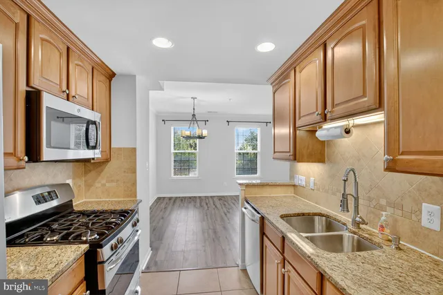 a kitchen that has a sink wooden floor and stainless steel appliances