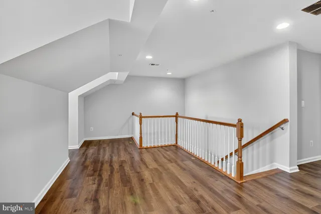 a view of an empty room with wooden floor and window