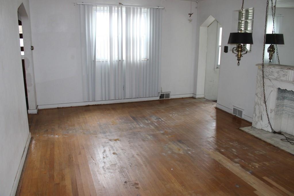825 Liberty Street Duquesne, PA 15110 - Photo 6 of 25 an empty room with wooden floor and a fireplace