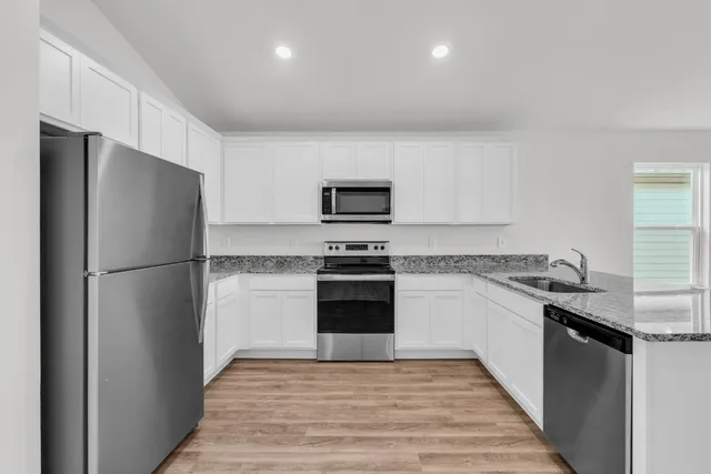 a kitchen with granite countertop a refrigerator stove and microwave