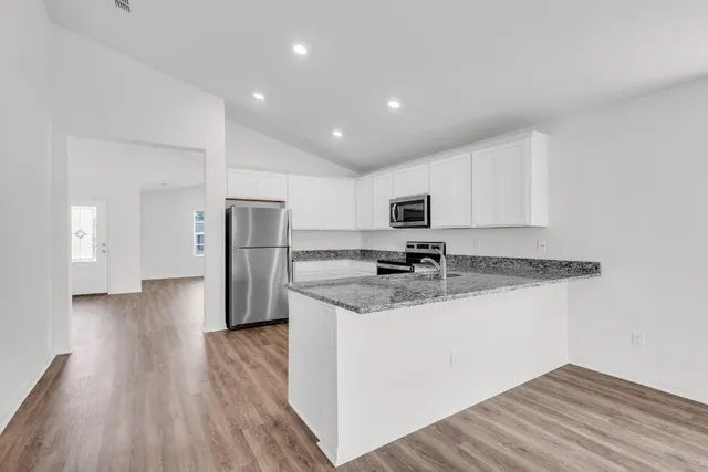 a kitchen with stainless steel appliances granite countertop a refrigerator and a stove top oven