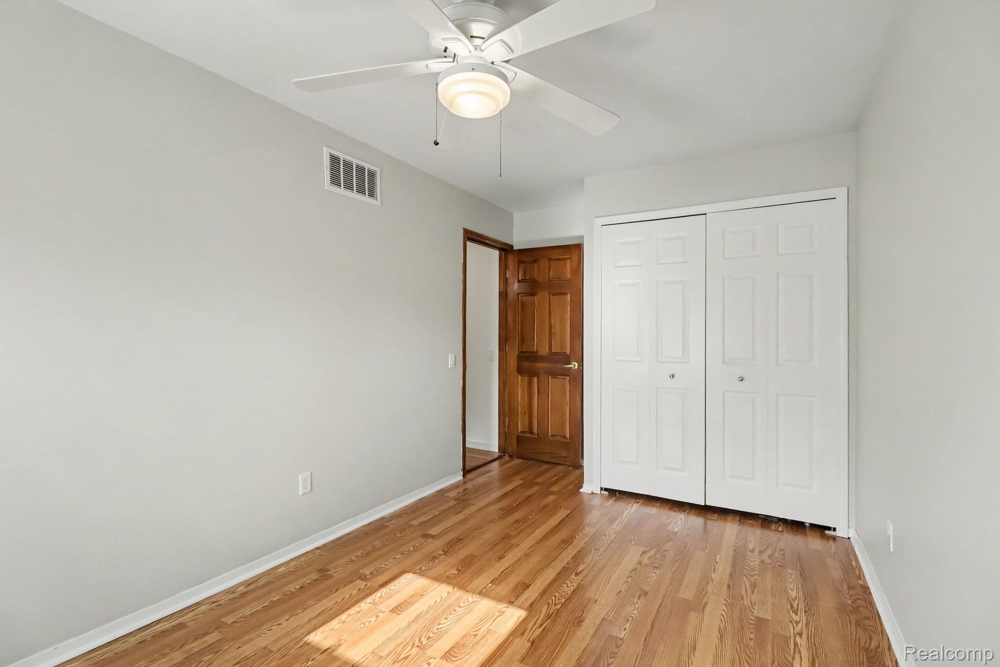 24404 Jamestowne Road Novi, MI 48375 - Photo 17 of 26 Hardwood flooring, painted walls, white ceiling fan with integrated lighting, and a bi-fold closet