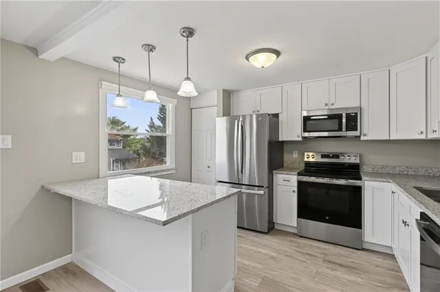 a kitchen with granite countertop a refrigerator a stove a microwave oven a sink and dishwasher with wooden floor