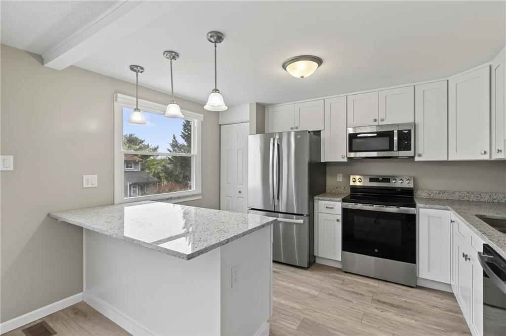 518 Hemlock Court Coraopolis, PA 15108 - Photo 12 of 34 a kitchen with granite countertop a refrigerator a stove a microwave oven a sink and dishwasher with wooden floor