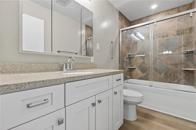 a bathroom with a granite countertop sink a toilet and shower