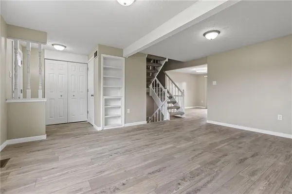 a view of an empty room with wooden floor and stairs