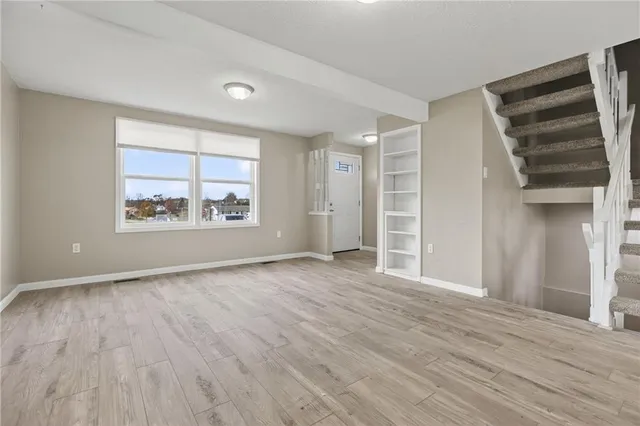 an empty room with wooden floor closet and windows